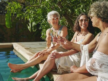 Three women relaxing by a pool in early retirement.