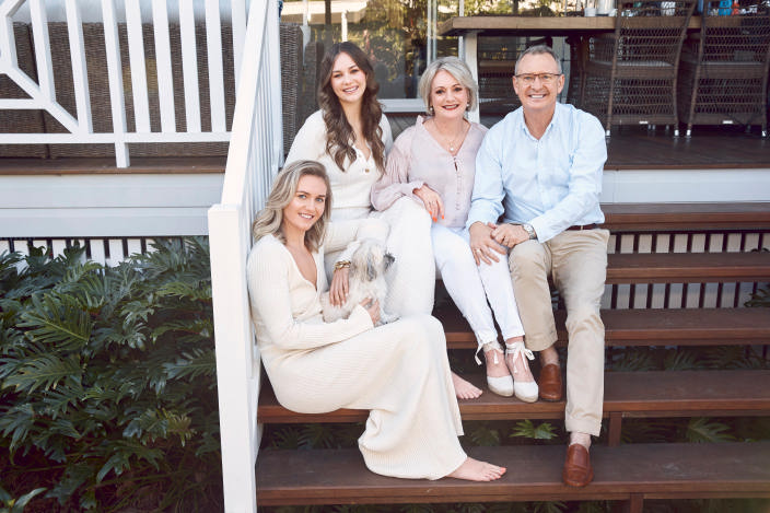 Ariarne sits on the wooden steps of her family home with sister Mia, mum Robyn, dad Steve, and Lucy, the family dog.